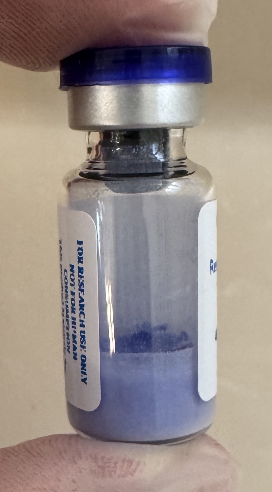 Blue lyophilized GHK-Cu copper tripeptide 50mg powder cake inside the sealed vial